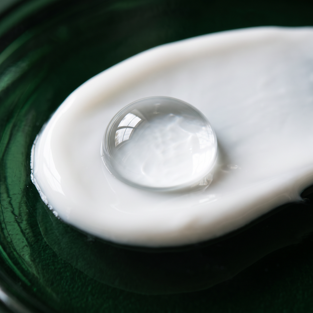 A water drop resting on a film of the cream